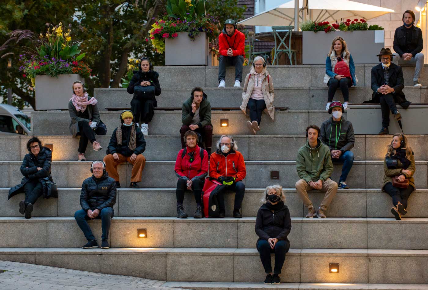 Teilnehmer des Audiowalks Remote Ludwigsburg sitzen mit Kopfhörern auf einer Treppe.